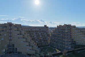 A high-rise residential building with multiple balconies, a central courtyard, and a clear view of the surrounding landscape.