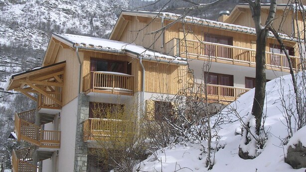 A wooden chalet with multiple balconies, set against a snowy mountainous backdrop. - Apartment in 3 Vallees With Pool & Sauna (Orelle)