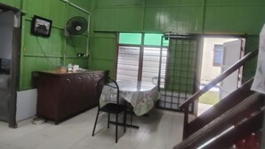 A room with green walls, a wooden cabinet, a table with a chair, and a staircase.