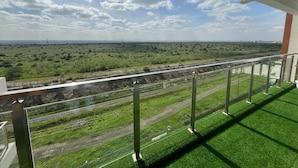 A balcony with a view of a railway track and green landscape. - Parkview Cribs. Serene 3BR with a DSQ near JKIA and SGR with National park view. (Nairobi)