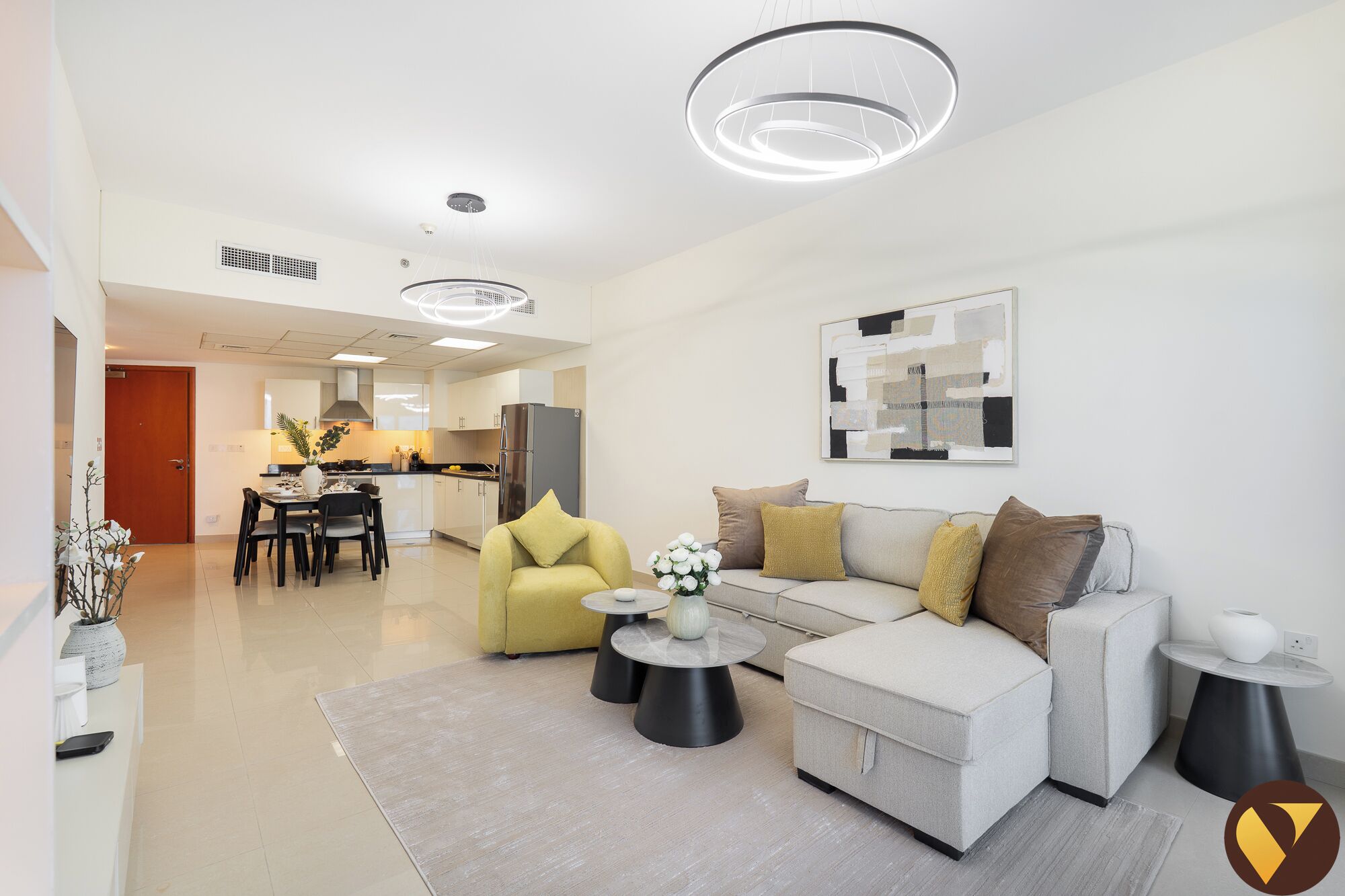 A modern living room with a sofa, coffee table, and a dining area with chairs and a table.