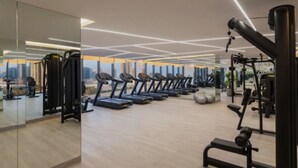 Un gimnasio moderno con cintas de correr, máquinas de pesas y un espejo grande que refleja el espacio.