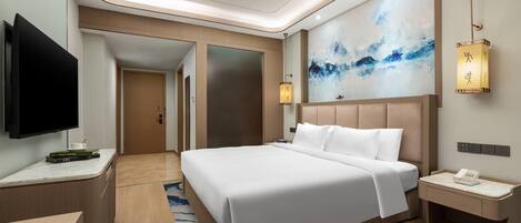 A modern hotel room with a large bed, a flat-screen TV, a desk, and a nightstand with a phone.