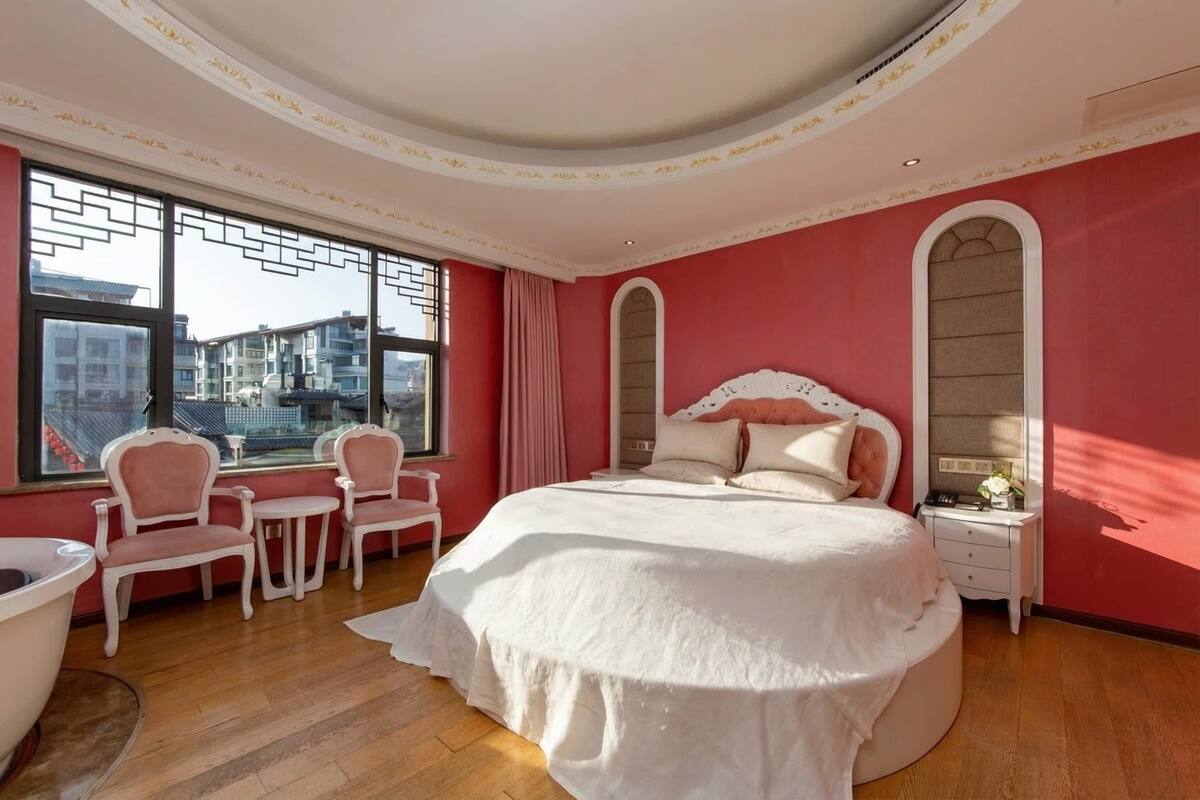 Un dormitorio con una cama grande, un tocador y una zona de estar con sillas.