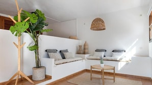 A living room with a sofa, a small table, a potted plant, and a hanging light fixture. - Villa Casa FOUR (Can Pep Simó)