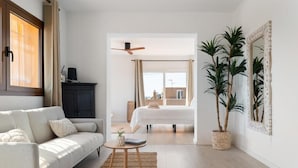 A modern living room with a sofa, coffee table, and a view into a bedroom. - Villa Casa FOUR (Can Pep Simó)