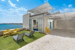 Ein moderner Außenbereich mit Pool, gelben Stühlen und einer Glastür zum Poolbereich.