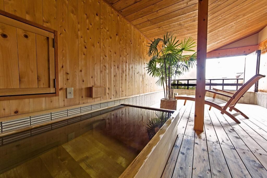 A wooden spa with a hot tub, wooden deck, and a large plant.