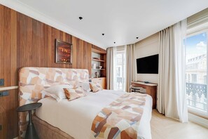 Ein modernes Hotelzimmer mit einem großen Bett, einem Schreibtisch, einem Fernseher und einem Balkon mit Blick auf die Stadt.