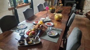 Una mesa de comedor lista con alimentos para el desayuno, como cruasanes, frutas y bebidas.