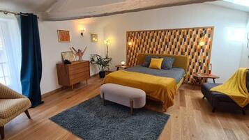 A bedroom with a bed, a chair, a dresser, a nightstand, and a small table.
