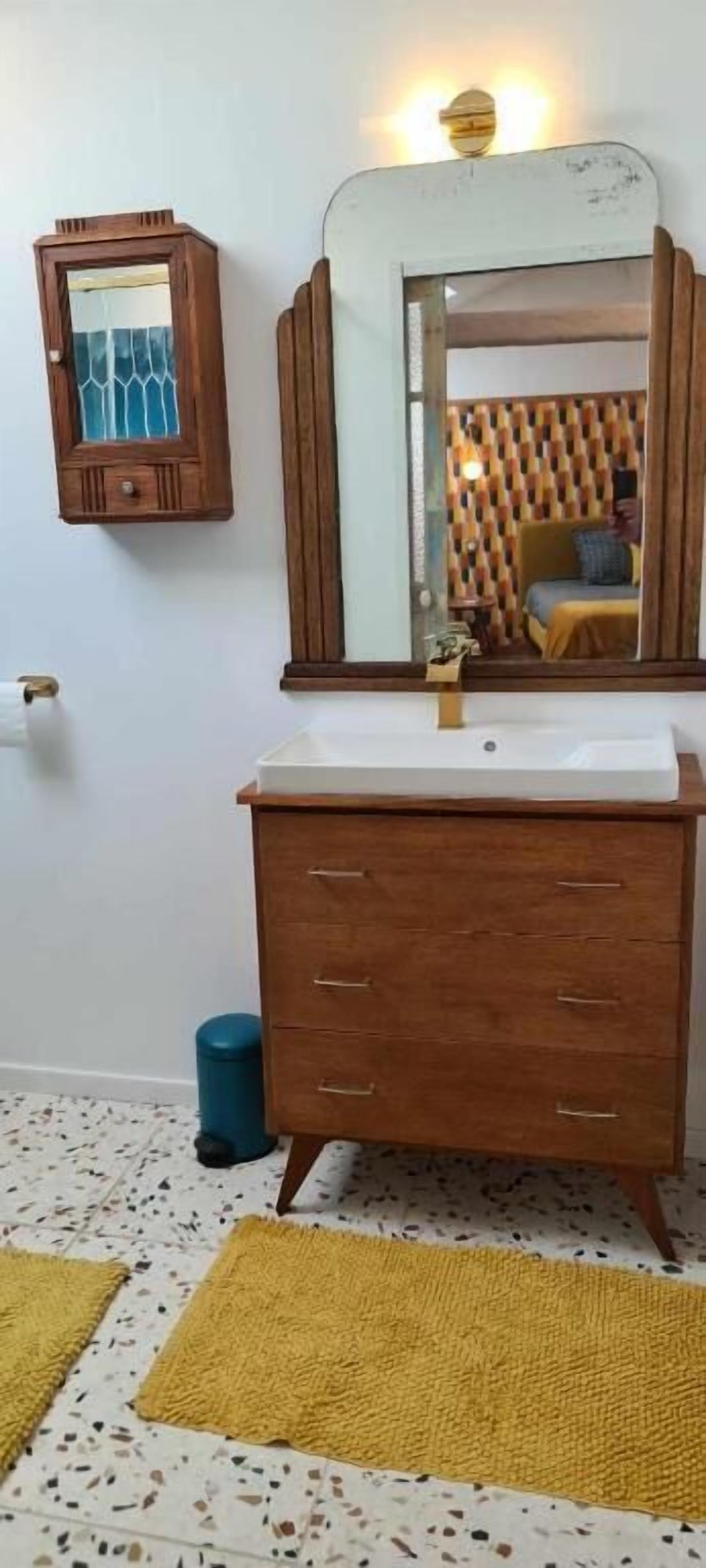 A bathroom with a wooden vanity, a mirror, and a toilet.