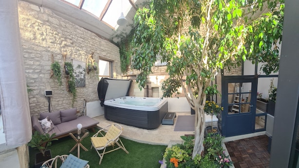 Un jardín interior acogedor con pared de piedra, jacuzzi y diversas opciones de asientos.