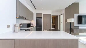 A modern kitchen with a central island, built-in appliances, and a flat-screen TV mounted on the wall.