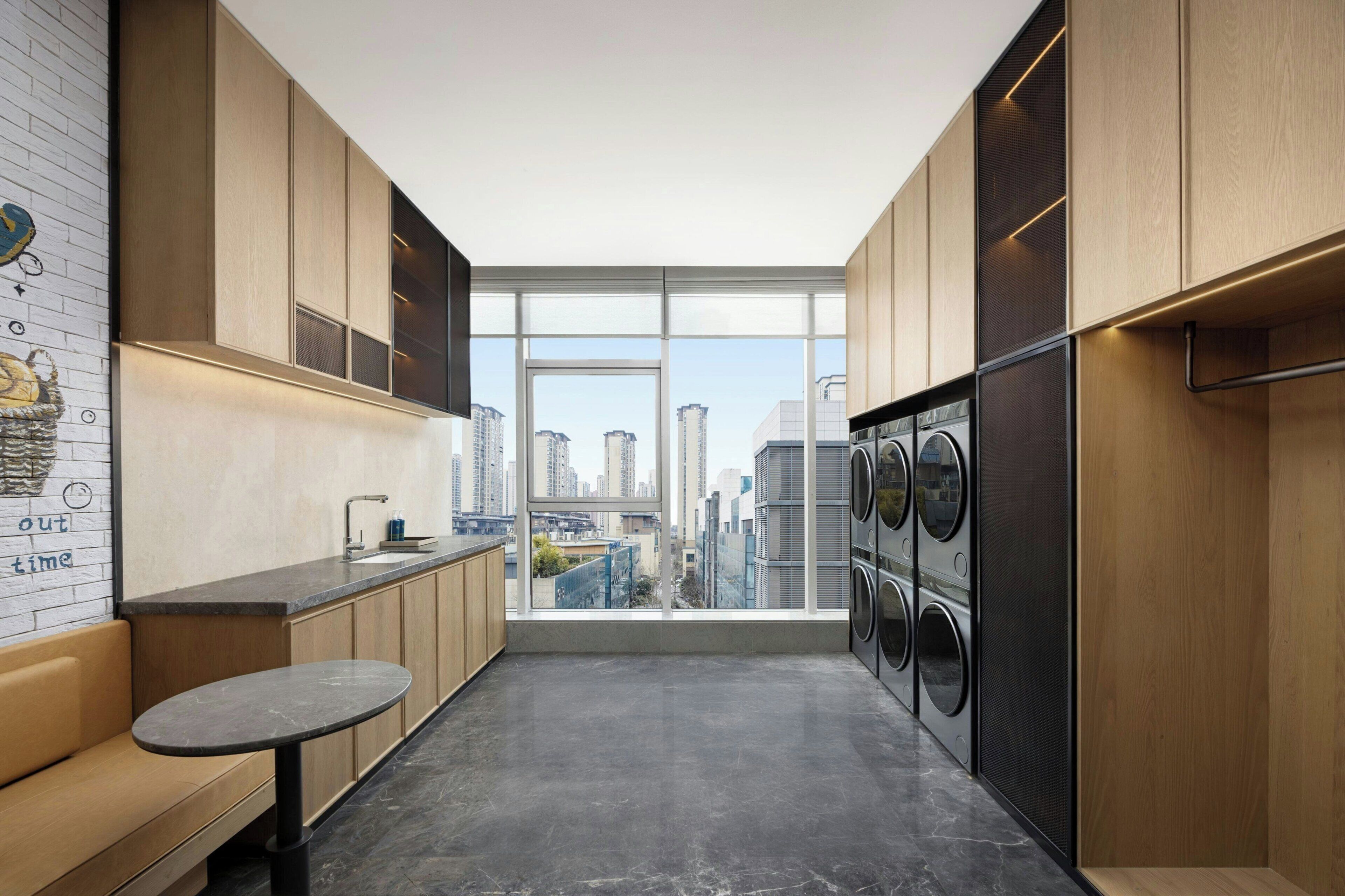 Una cocina moderna con vista a la ciudad, lavadora integrada y una pequeña mesa.