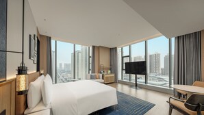 A modern hotel room with a large bed, a desk, a chair, a TV, and a city view. - Four Points by Sheraton Hanzhong Riverside (Hanzhong)