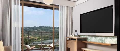 A modern living room with a large TV, a dining area, and a view of a lake.
