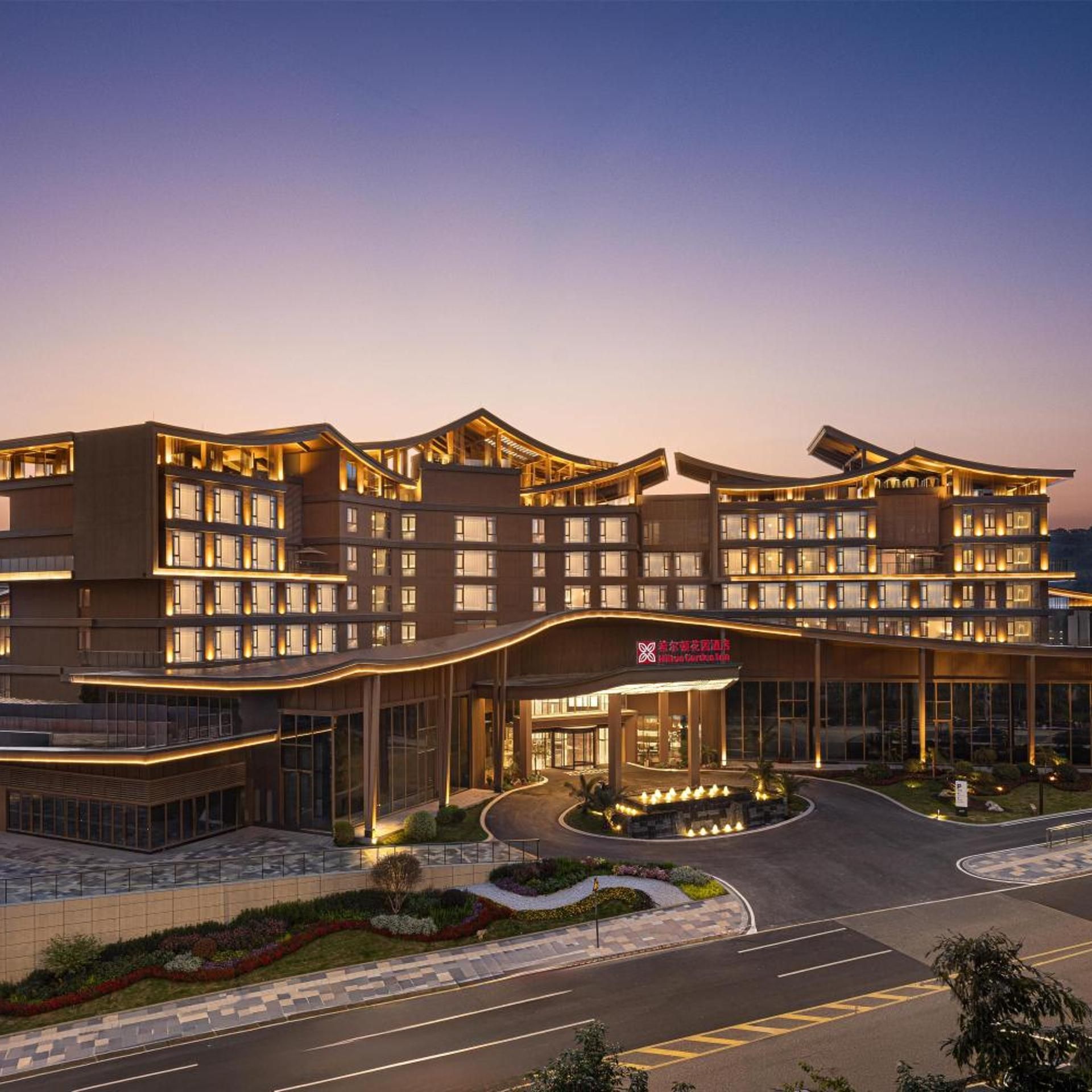 A multi-story hotel with a modern architectural design, featuring a prominent entrance and a landscaped driveway.