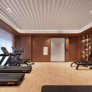 Un gimnasio con cintas de correr, elípticas y bancos de pesas.
