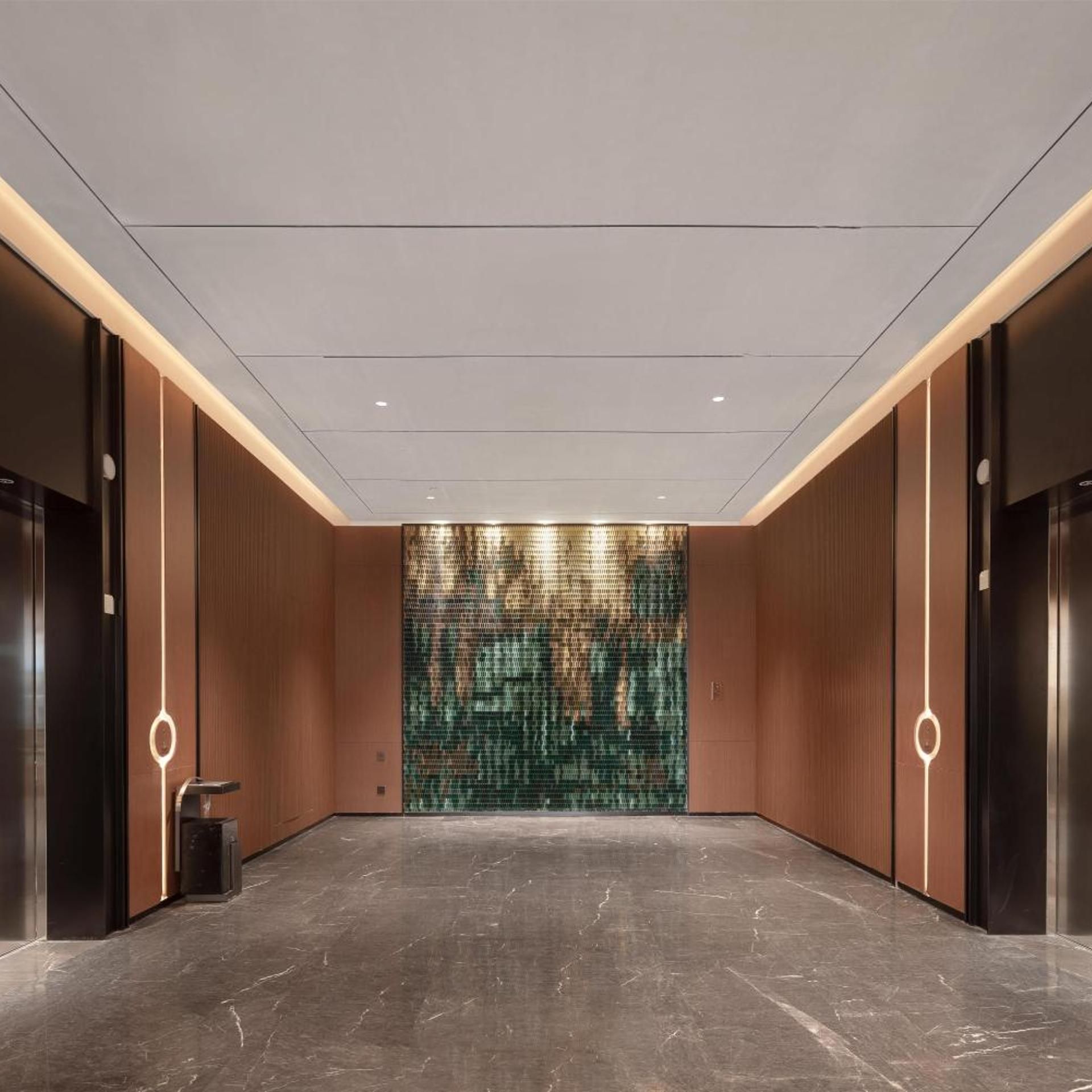 A modern elevator lobby with a marble floor and a textured wall.