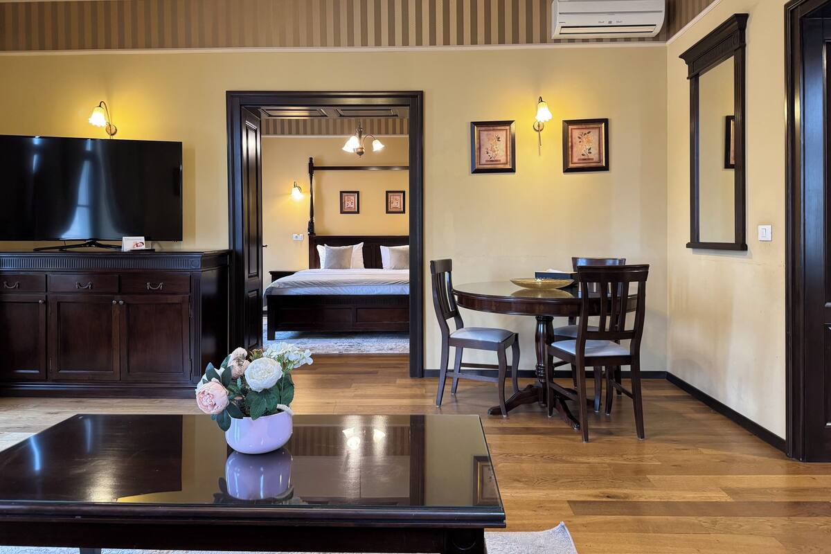 A hotel room with a bed, a desk, a TV, and a dining table.