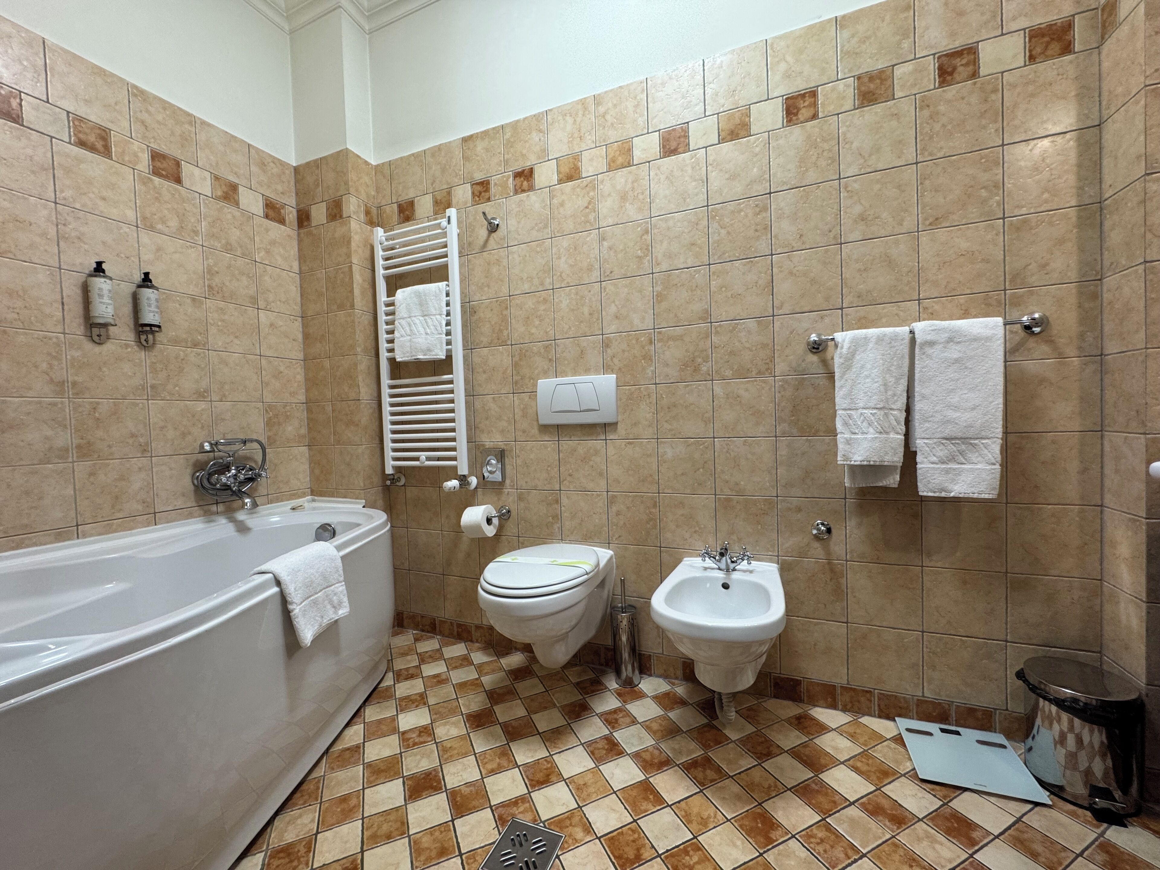 Casa de banho com banheira, sanita, bidé e porta-toalhas.