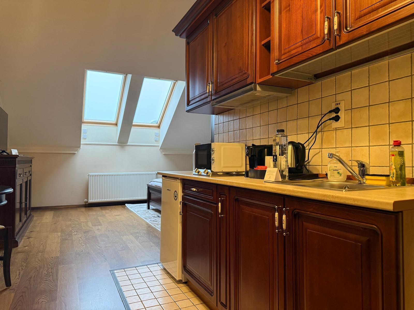 Eine Küche mit Holdelementen, einer Arbeitsplatte, einem Toaster, einem Wasserkocher und einem Spülbecken mit Armatur. Über den Fenstern befinden sich Dachfenster.