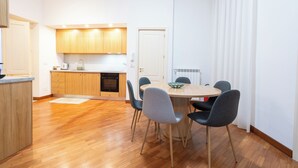 Eine moderne Küche mit Holzschränken, einem Esstisch mit Stühlen und einer weißen Tür.