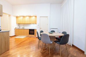 A modern kitchen with wooden cabinets, a dining table with chairs, and a white door. - Appartamento 150 mq. per famiglie e gruppi di amici (Catania)