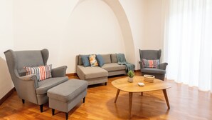 Ein modernes Wohnzimmer mit grauem Sofagarnitur, zwei Sesseln, einem Couchtisch und Holzboden.