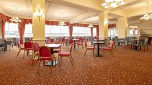 A hotel dining area with tables and chairs, large windows, and chandeliers. - Executive Double Room (Bournemouth)