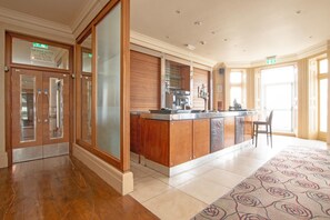 Eine Hotelhalle mit einer Rezeption, einer Kaffeemaschine und einer Sitzecke.