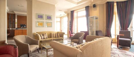 A spacious living room with a sofa set, armchairs, a coffee table, and a television.
