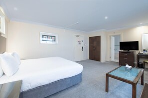 A hotel room with a bed, a desk, a television, and a door leading to another room. - Executive Double Room (Bournemouth)