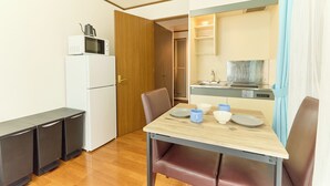 A compact kitchen with a microwave, a refrigerator, and a small dining table with chairs. - Dream Terrace One Casa Dali (Tokyo)