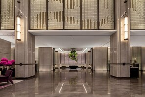 A modern lobby with a reflective floor, a central plant, and symmetrical lighting fixtures. - La Quinta by Wyndham Qinzhou Qinnan (Qinzhou)
