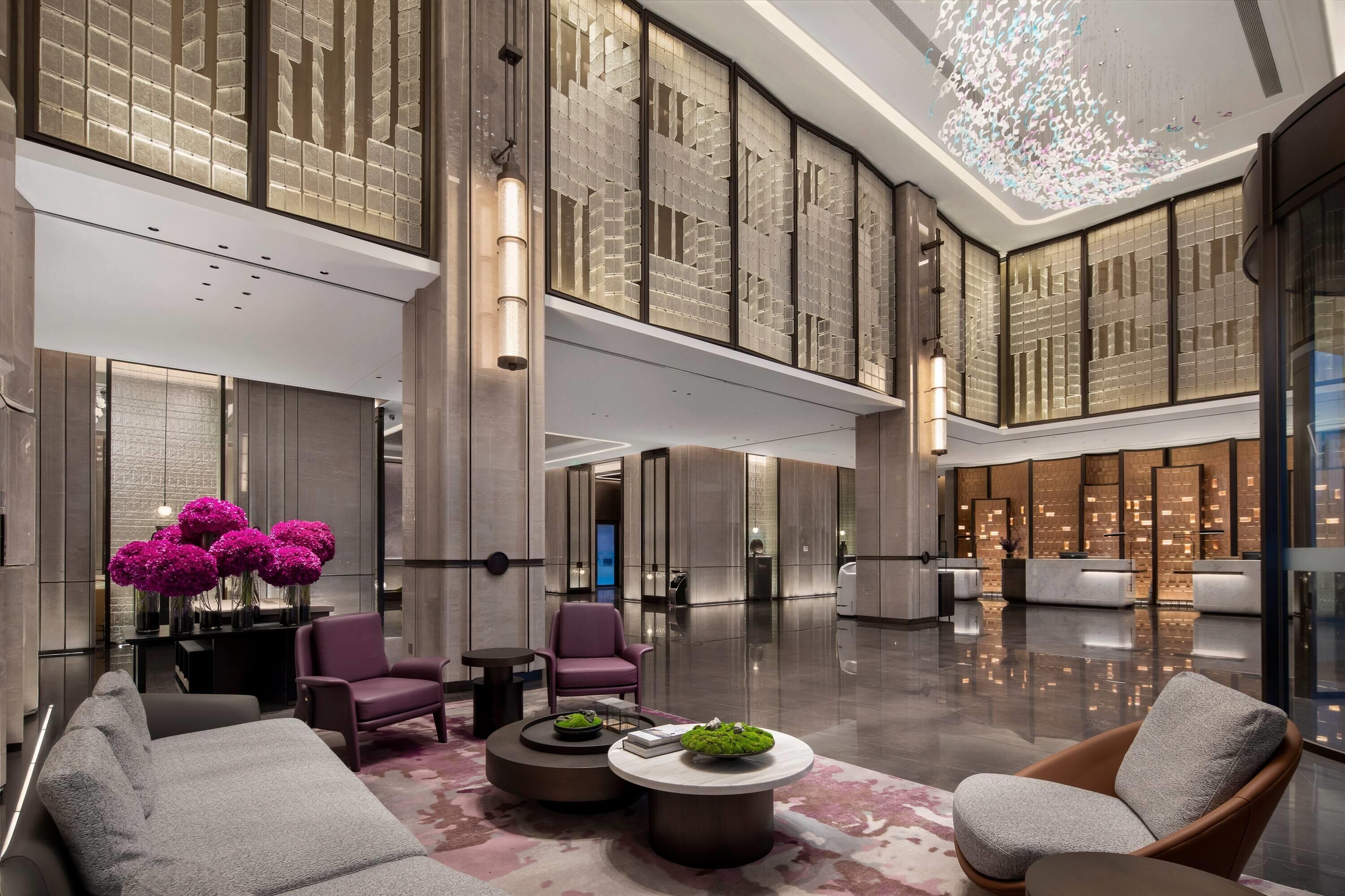 A spacious lobby with high ceilings, modern furnishings, and a central seating area with a coffee table.