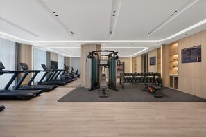 A modern gym with treadmills, elliptical machines, a squat rack, and dumbbells.