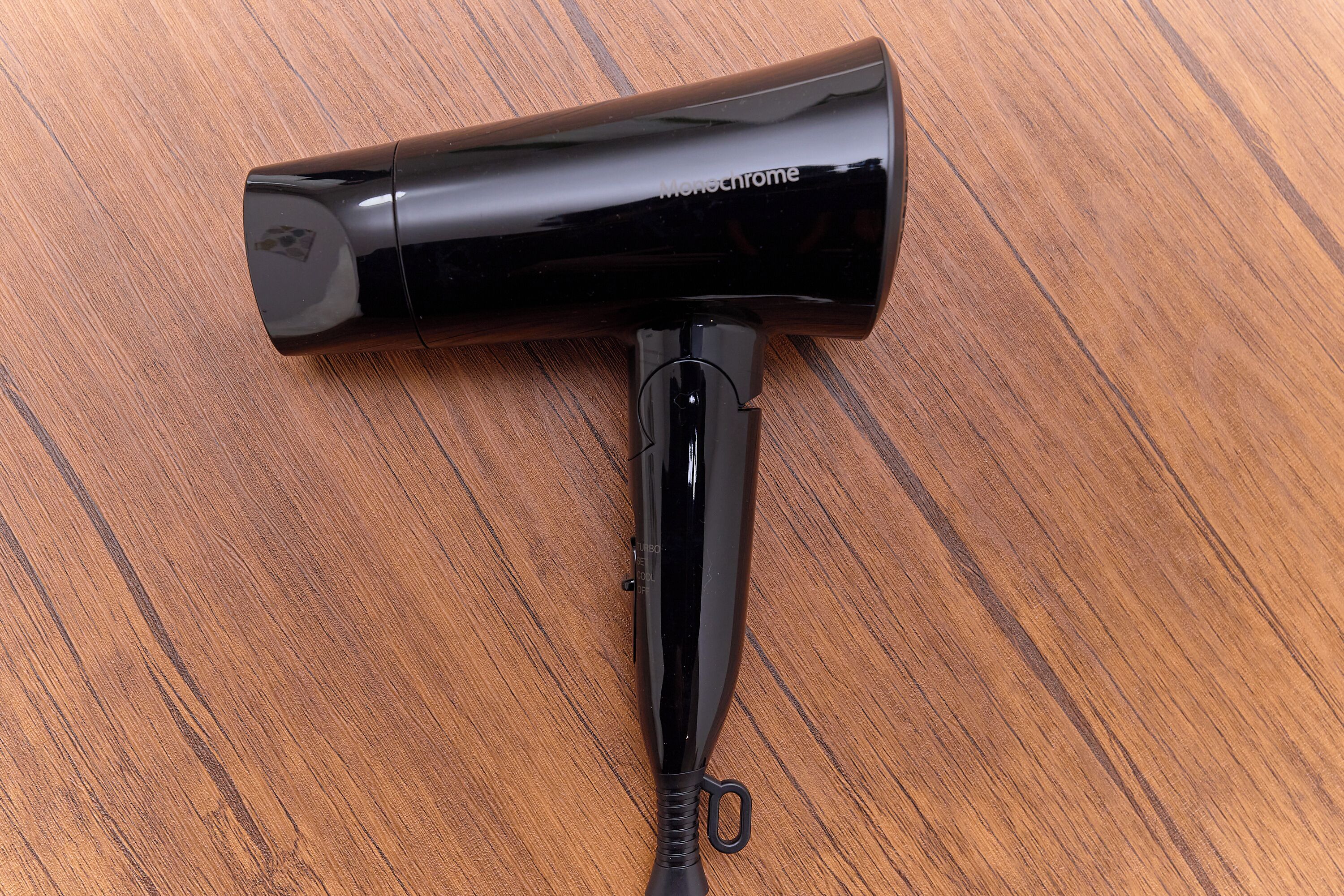 A black hairdryer on a wooden surface.