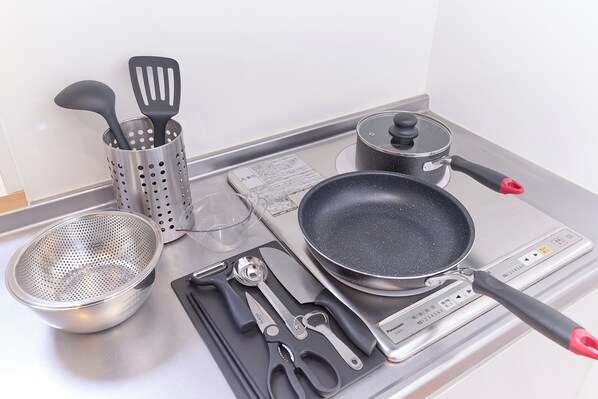 A kitchen with a stove, a frying pan, a colander, a spatula, a pair of scissors, and a pot. - Zenith Nakano Shinbashi (Tokyo)