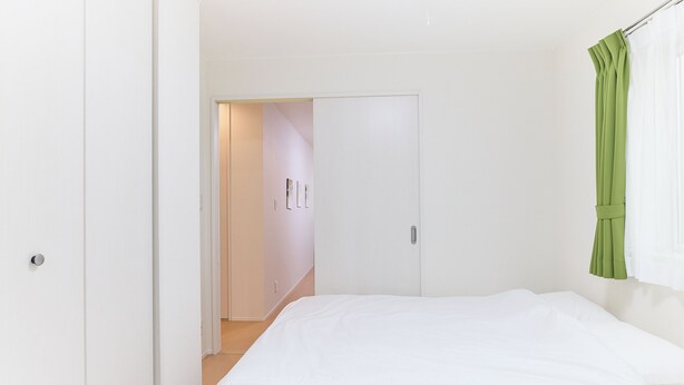 A bedroom with a bed, a door, and a green curtain. - Zenith Nakano Shinbashi (Tokyo)