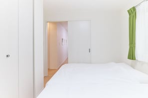 A bedroom with a bed, a door, and a green curtain. - Zenith Nakano Shinbashi (Tokyo)