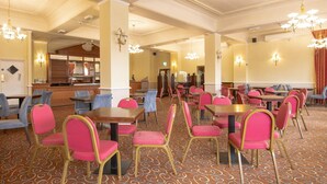 A hotel dining area with multiple tables and chairs, a patterned carpet, and chandeliers. - Standard family room for 4(2A+2C) (Bournemouth)