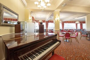 A grand piano in a hotel dining area with red upholstered chairs and a patterned carpet. - Bournemouth East Cliff by Belvilla - Superior Feature w/ View (Bournemouth)