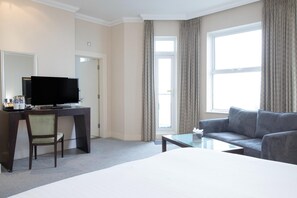 A hotel room with a bed, a desk with a computer, a chair, a sofa, a coffee table, and a window with curtains. - Bournemouth East Cliff by Belvilla - Superior Feature w/ View (Bournemouth)
