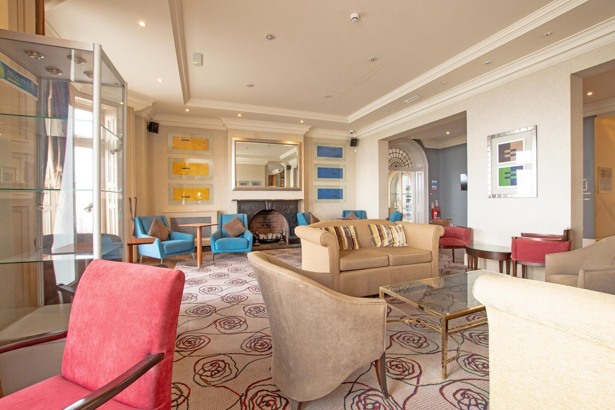 A spacious living room with a fireplace, comfortable seating, and a patterned carpet.
