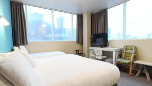 Une chambre d’hôtel avec un grand lit, un bureau avec un ordinateur, une télévision et une chaise.