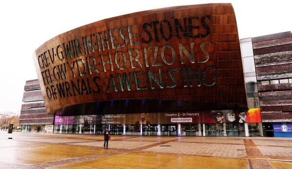 A modern building with a curved facade and large text reading "CREW IN THE STONES THE LAWYER FOR HORIZONS OF WRNAI'S AMENESS". - Standard Family of 3 Room (Cardiff)