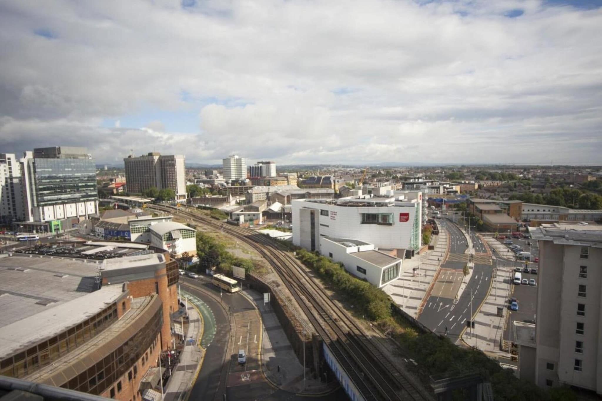 A cityscape with modern buildings, a curved road, and a train track.