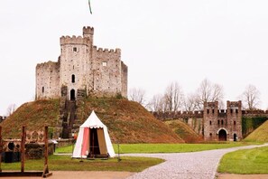 A castle with a large entrance gate, a small tent, and a paved pathway leading to the castle. - Standard Triple Room (Cardiff)